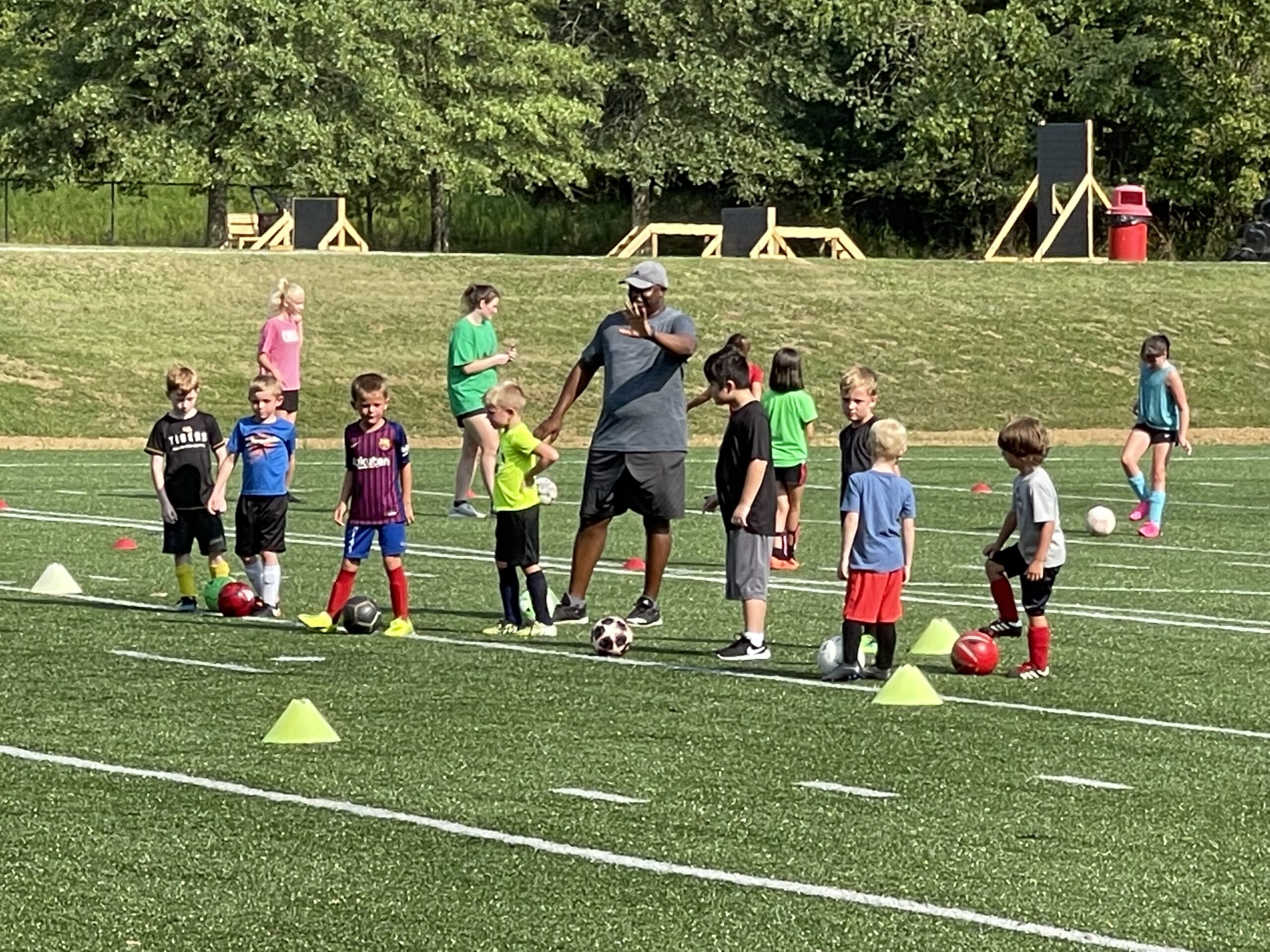 african american soccer coach instructing youth outdoors