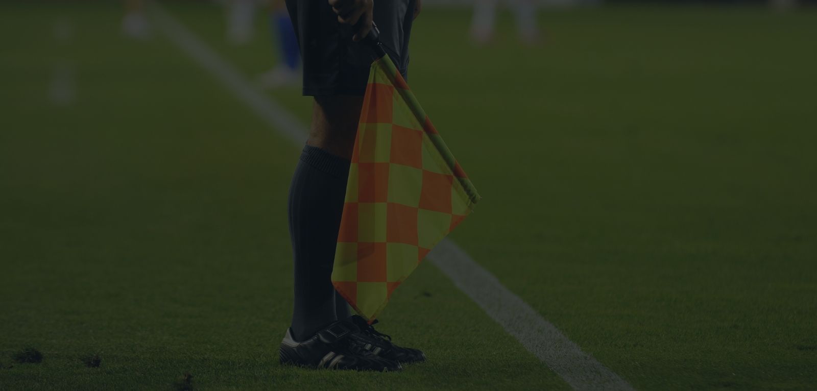 Assistant soccer referee standing on the touchline with his flag pointed down